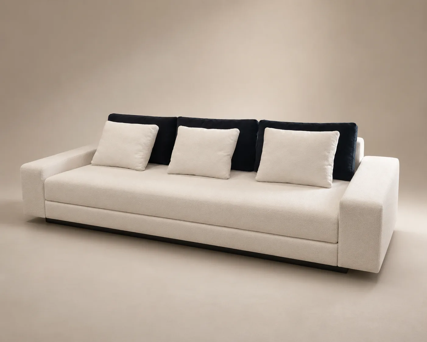 The Étienne lounge sofa — a long, low ivory seat anchored by ink-dark bolsters.