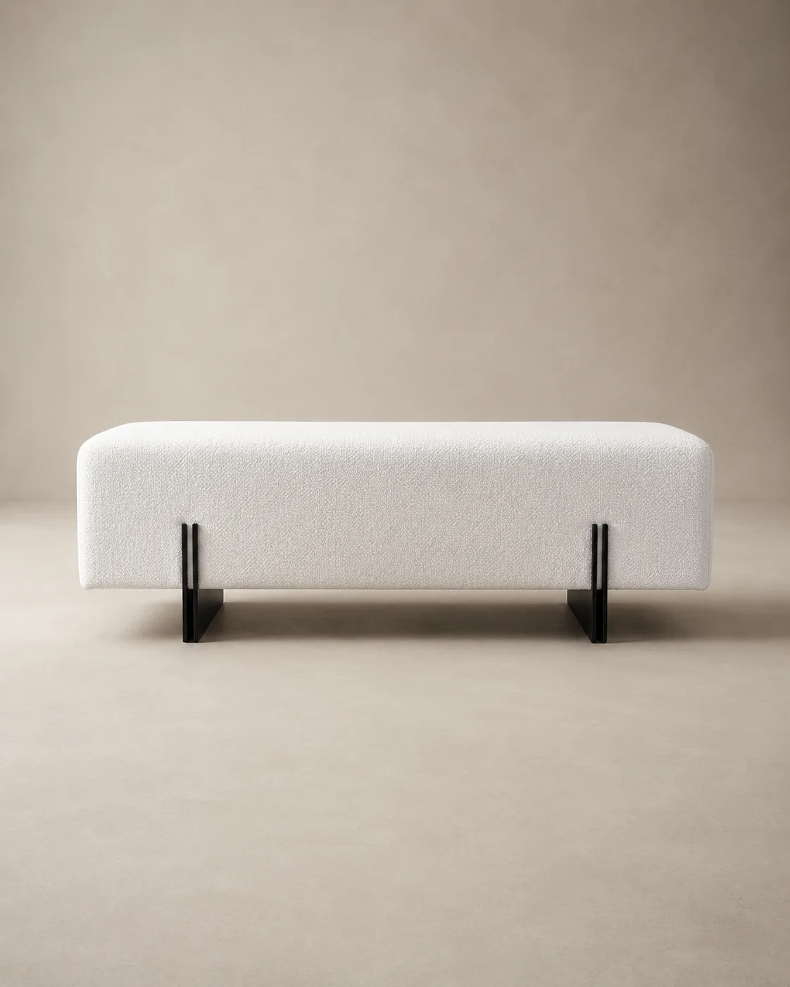 The Lisière bench — a clean ivory bouclé volume lifted on slender blackened-steel legs.